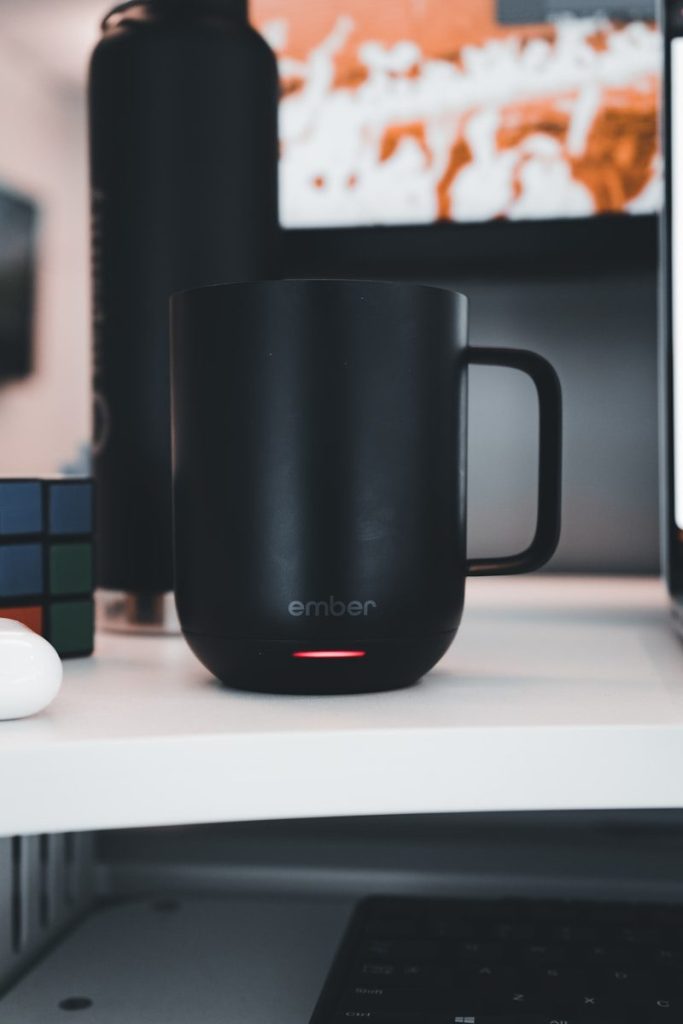 a black mug sitting on top of a white desk